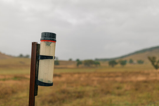 Rain gauge on rural farm property measuring rainfall on stormy day