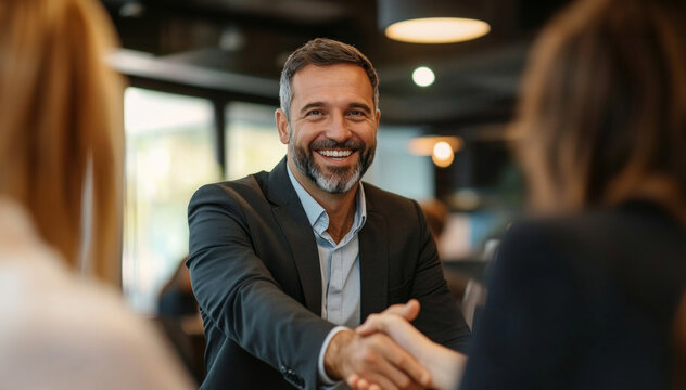 In a bright office setting, a financial expert shakes hands with pleased customers, all smiling and engaged in a conversation about financial solutions.