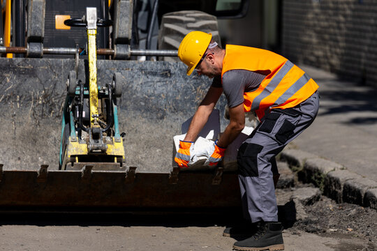 Construction worker handling materials on a busy urban street during daylight hours