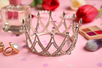 Tiara with makeup products, perfume and tulip flowers on pink background. Prom concept