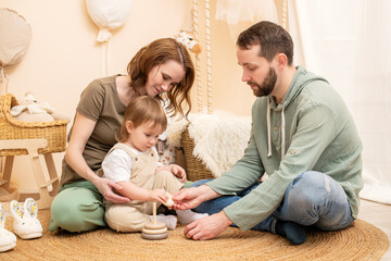 loving young family enjoys quality time together in a beautifully decorated nursery. The parents engage their toddler in an educational game, creating a warm and joyful atmosphere