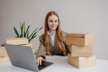 Woman working at desk with laptop and wooden boxes in a modern office setting during daytime
