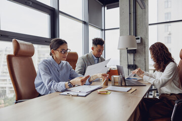 A diverse and talented team is engaged in a collaborative office meeting filled with important documents and laptops