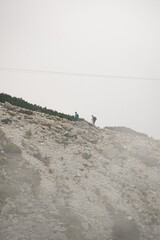 Two people hiking up a mountain ridge with hiking polen and fog, High Tatra National Park, Slovakia