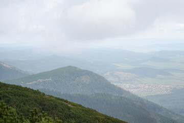 Fototapeta premium Areal view of green mountains with agricultural fields in the backgrounds and low clouds, High Tatra National Park, Slovakia