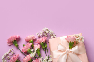 Gift box with beautiful carnation and gypsophila flowers on lilac background. Mother's Day...