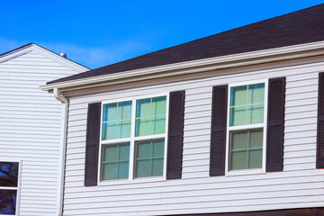 Modern house features white siding, black shutters, large windows enhances appearance of this attractive residential building at American town