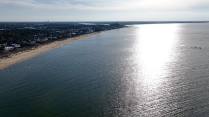 Fototapeta premium Virginia Beach, VA coastline at sunset with sandy beach and resorts with beach house by calm peaceful water reflecting sunlight