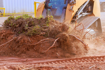 Bulldozer is clearing away soil at construction site during preparing land for development © ungvar