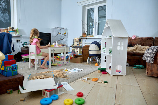 Child Playing in Messy Room Surrounded by Toys