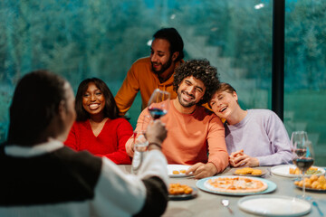 Friends raising glasses, making a toast during dinner party at home