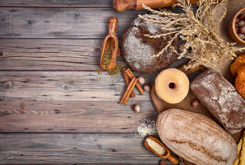 Fresh homemade bread and cake with sugar crispy baking on rustic wooden boards surface. Place for text. Kraft bakery background.