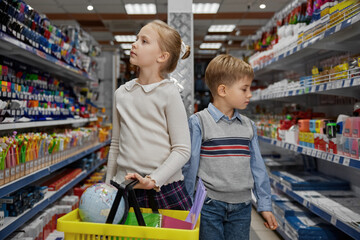 Schoolchildren doing shopping at stationery store walking through shelves