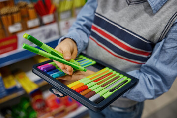 Closeup hands of unrecognizable boy holding colorful markers in pack