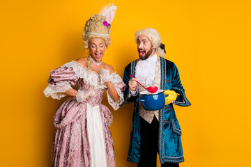 Fototapeta premium Elegant royal couple in vintage costumes having fun against a bright yellow backdrop