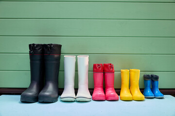 Colorful Array of Rain Boots Against a Green Wall