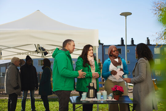 Male and female volunteers standing with neighbors in public park