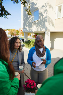 Woman wearing headscarf listening to volunteers explaining about charity work at park