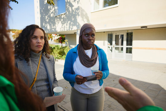 Female friends holding listening to volunteer explaining about charity work at park
