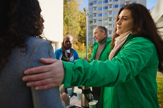 Female volunteer consoling woman with hand on shoulder at park