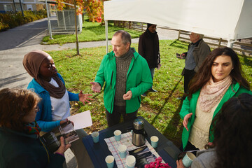 High angle view of male volunteer discussing about charity program with neighbors at park