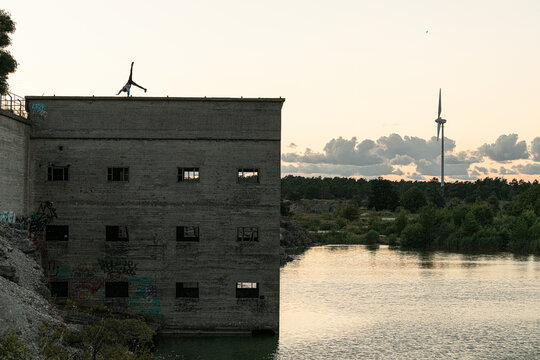 Unrecognizable person doing cartwheel on top of abandoned building at dawn