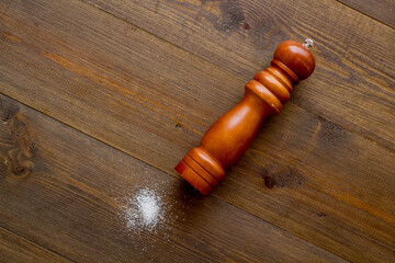 Wooden salt shaker and pile of spilled salt, top view. Cooking concept
