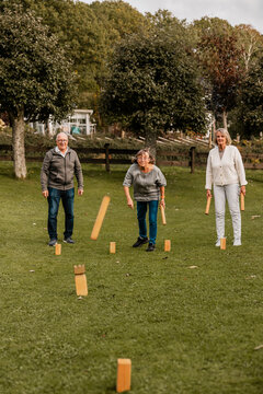 Carefree senior woman playing Molly game with male and female friend in back yard