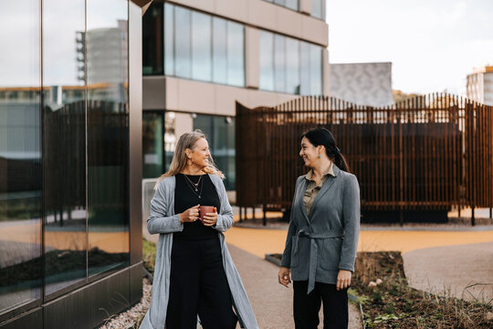 Female entrepreneurs talking with each other during coffee break outside office building