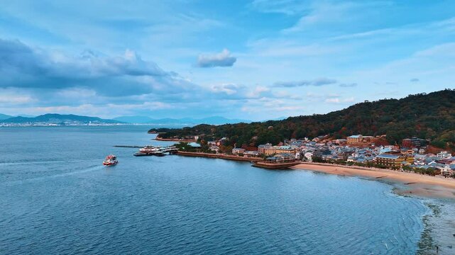 Approaching the shore of the Seto Inland Sea with picturesque houses and beautiful nature. Aerial perspective on the mountains and cloudscape above the rocks. Japan sightseeing.