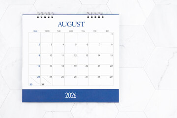 August 2026 desk calendar on white marble tiles background.