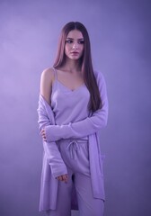 Fototapeta premium Young female in lavender outfit posing against purple background