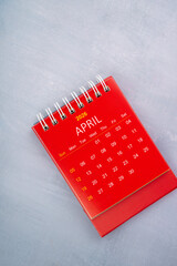April 2026 red color calendar on wooden background.