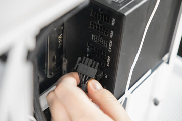 Technician plugging black power cable into modular PSU port labeled P8 inside computer case during...