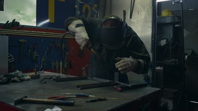 Welder operator wearing personal protective equipment working in the welding workshop, fusing steel parts together, using MIG welding proccess medium shot. Metal industry concepts.