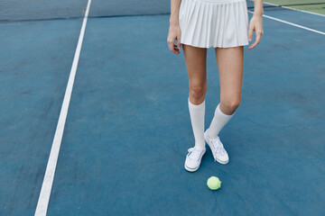 Female tennis player in a sporty white outfit standing on a blue court, showcasing athleticism,...