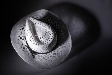White cowboy hat casting a shadow on dark background