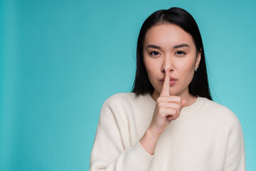 Serious Asian woman girl female student holding finger on lips mouth keep it quiet secret information showing hush shh shush gesture isolated on light bright studio background