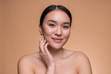 Woman with beautiful face touching healthy facial clean skin. Attractive smiling Asian model with...