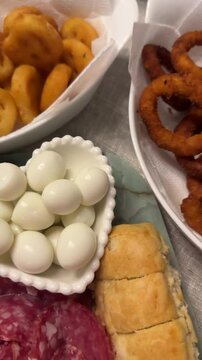 tabua com alimentos frios, ovos, salame, cebola, p&atilde;o  e pepinos 