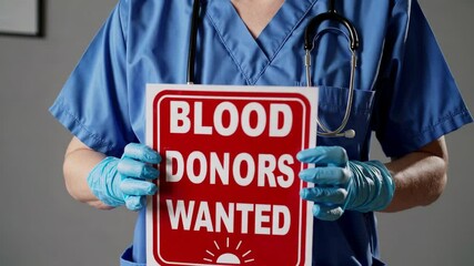 Medical professional in blue scrubs and gloves displaying urgent blood donation sign, highlighting critical need for donor support and community involvement