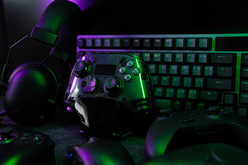 gamer work space concept, top view a gaming gear, mouse, keyboard, joystick, headset, mobile joystick, in ear headphone and mouse pad with rgb color on black table background.
