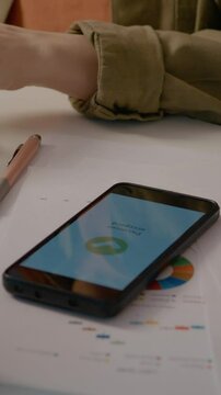 Vertical Screen: Woman types on her computer in a home office, then checks her phone to confirm if the online payment has been accepted during her workday.