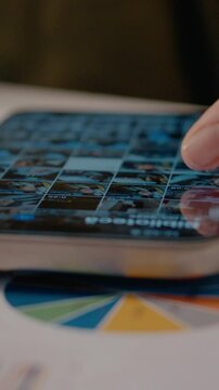 Vertical Screen: Businesswoman scrolling through pictures on her phone while taking a break at her home office desk