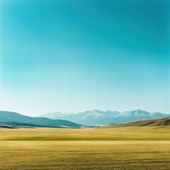 A wide-open field with a distant mountain range on the horizon, the field of grass stretching endlessly toward the mountains under a vast, clear sky, capturing the natural scale of the landscape