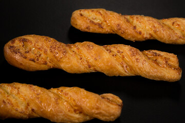 Cheese sticks made from puff pastry on a black background, top view