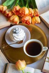 Cup of tea and cake on the table with beautiful spring flowers tulips.