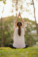 Young Asian woman practicing yoga in a quiet park, gracefully in a relaxed pose, relaxing and...
