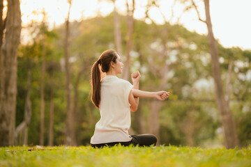 Young Asian woman practicing yoga in a quiet park, gracefully in a relaxed pose, relaxing and...
