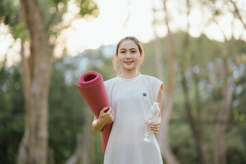 Young Asian woman practicing yoga in a quiet park, gracefully in a relaxed pose, relaxing and...